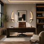 Black crescent arc LED wall lights flanking a desk and artwork in a sophisticated home study