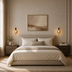 Gold black bare bulb industrial wall sconces used as bedside reading lights flanking artwork in neutral elegant bedroom
