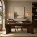 Gold black bare bulb industrial wall sconces flanking framed art above desk in dark wood panelled home office