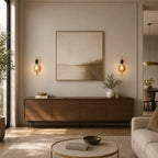 Gold black bare bulb industrial wall sconces flanking framed artwork above dark sideboard console in warm living room