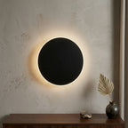 Black halo LED modern wall light — circular backlit disc with discreet motion sensor for hands-free hallway illumination.