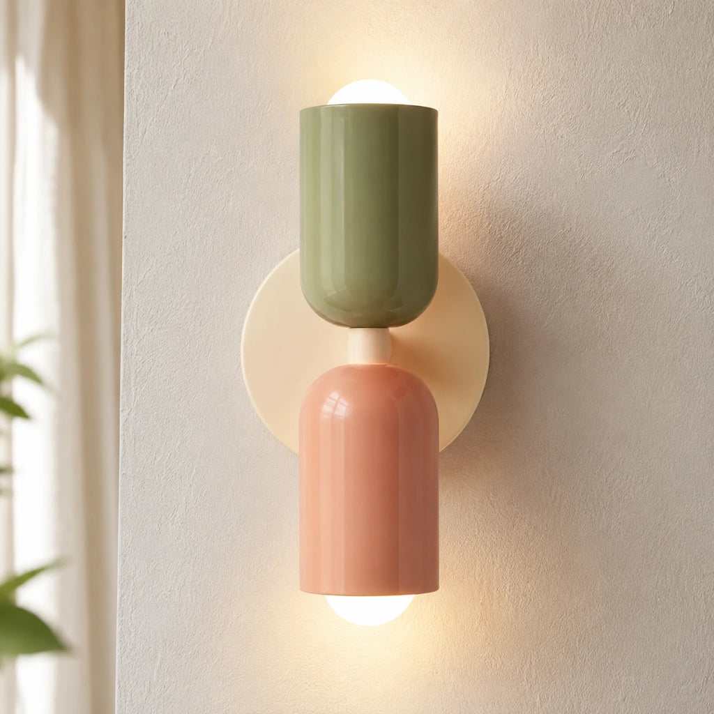 Colourful Nordic indoor wall light — green and pink cylindrical shades on a cream backplate for a bohemian earthy palette.
