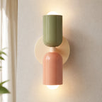 Colourful Nordic indoor wall light — green and pink cylindrical shades on a cream backplate for a bohemian earthy palette.