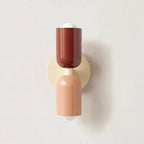 Colourful Nordic metal wall light with two cylindrical shades in red and pink on a cream base, casting light up and down