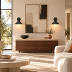 Black cone arm industrial wall sconce mounted on a living room wall, redirecting its swing arm toward a reading chair.