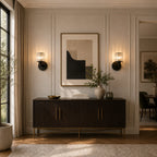 Black crystal cylinder Art Deco wall sconces flanking framed artwork above dark sideboard console in elegant living room