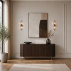 Silver column crystal glass Art Deco wall sconces flanking abstract art above dark sideboard in airy living room