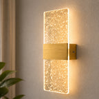 Decorative acrylic contemporary LED wall sconce with sparkling crystal panel and brushed gold hardware on neutral wall background