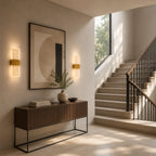 Gold decorative acrylic contemporary LED wall sconces flanking abstract art above console table in modern staircase entryway