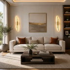 Gold double strip LED wall lights flanking a large artwork above a sofa in a warm contemporary living room