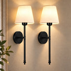 Pair of black fabric mid-century wireless wall sconces mounted together, each with a tapered fabric shade on a slim stem.