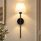 Black fabric mid-century wireless wall sconce mounted on the wall, featuring a tapered fabric shade on a slim metal stem.