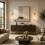 Gold glass loop arm Nordic wall sconces flanking framed artwork above sideboard console in bright modern living room