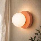 Mini Glass Orb Nordic Wall Light in pink, wide-angle view on textured wall with linen curtain