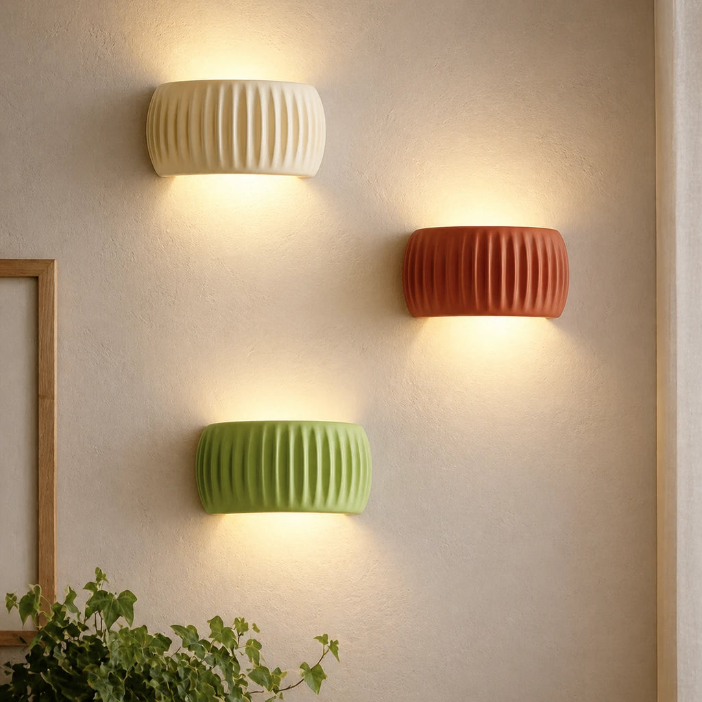 Ribbed resin Nordic wall light in sage green — ribbed cylindrical shade on a slim wall bracket for a natural Nordic bedroom.