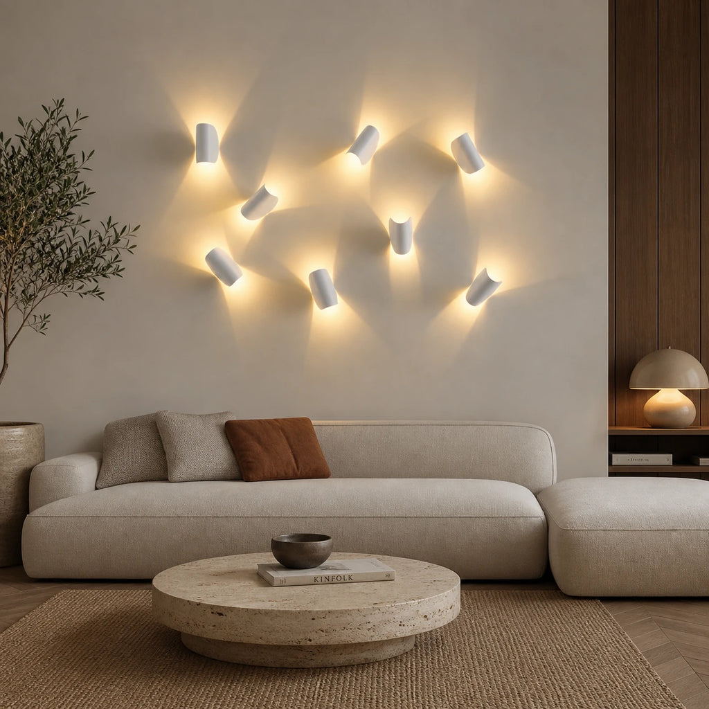 Gallery cluster of white rotating half-disc LED wall lights arranged artistically above a sofa in a modern living room