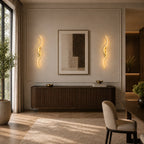 Gold sculptural dual-curve LED wall lights flanking a sideboard and artwork in an elegant open dining area