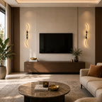 Black sculptural dual-curve LED wall lights flanking a TV wall unit in a warm modern living room with round coffee table