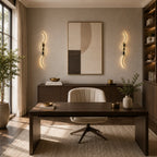 Black sculptural dual-curve LED wall lights flanking a desk and bookshelf in a sophisticated home study