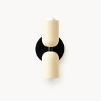 Two-tone Nordic indoor wall light — cream cylindrical shades on a black backplate for a monochrome contemporary Scandinavian finish.