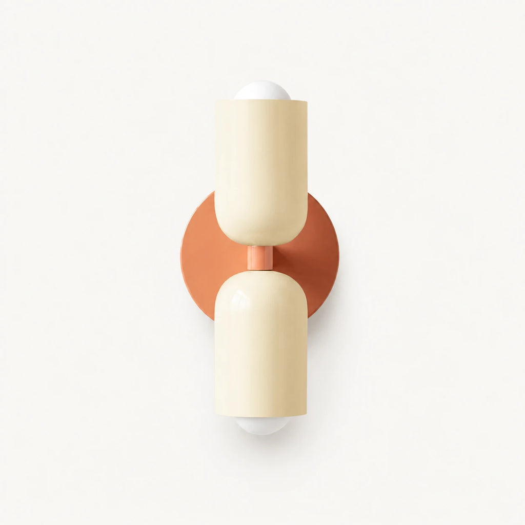 Two-tone Nordic indoor wall light — cream cylindrical shades on a pink backplate for a pastel Scandinavian bedroom accent.