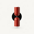 Two-tone Nordic indoor wall light — red cylindrical shades on a black circular backplate for a bold contrast statement wall.
