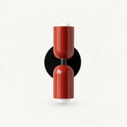 Two-tone Nordic indoor wall light — red cylindrical shades on a black circular backplate for a bold contrast statement wall.