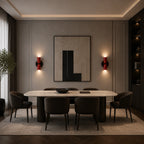 Pair of red two-tone Nordic up and down wall lights flanking bold abstract artwork in a moody dining room.